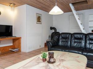 a living room with a black leather couch and a tv at 18 person holiday home in R m in Kongsmark