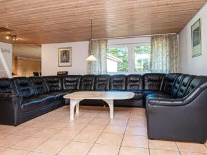 a living room with a black leather couch and a table at 18 person holiday home in R m in Kongsmark