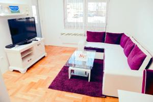 a living room with a white couch and a tv at Apartman Luna lukavica in Lukavica