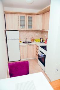 eine Küche mit einem weißen Kühlschrank und einem lila Stuhl in der Unterkunft Apartman Luna lukavica in Lukavica
