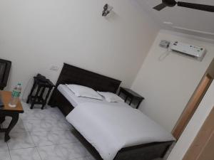 a bedroom with a bed with white sheets and a table at Hotel Victoria in Chandīgarh