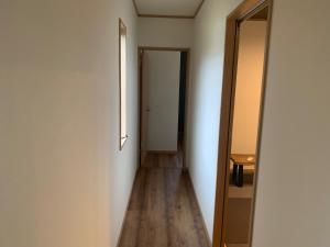 a hallway with white walls and wooden floors and a door at KAI Ichinomiya in Ichinomiya