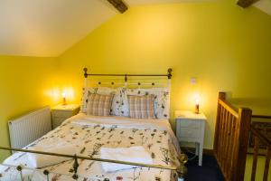 een slaapkamer met een bed met gele muren en 2 lampen bij The Sunshine Annex at Lower Fields Farm in Napton on the Hill