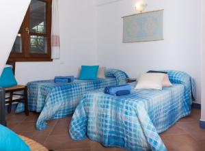 two beds in a room with blue sheets at La Casa dell'Artista in Orosei