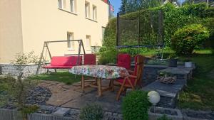een patio met 2 stoelen, een tafel en een schommel bij Ferienwohnung mit Garten und Spielplatz in Klingenthal