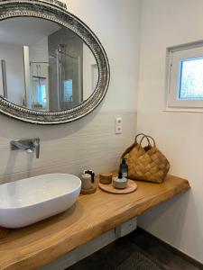 ein Badezimmer mit einem weißen Waschbecken und einem Spiegel in der Unterkunft Ferienhaus Siesta Hahnenklee mit großem Grundstück in Hahnenklee-Bockswiese