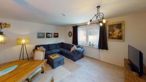 ein Wohnzimmer mit einem blauen Sofa und einem TV in der Unterkunft Ferienhaus Siesta Hahnenklee mit großem Grundstück in Hahnenklee-Bockswiese