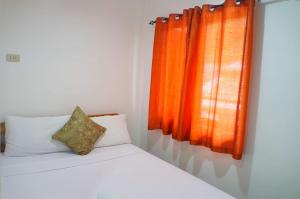 a bedroom with a bed with an orange curtain at Sheryl May Inn in El Nido