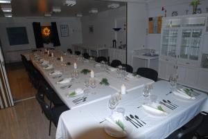 a long table in a room with white tables and chairs at Fossanåsen Hotel in Flesberg