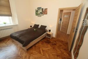 Un dormitorio con una cama y suelo de madera. en Apartments Sobieski&Soplica, en Cracovia