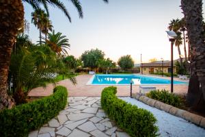- une piscine dans un complexe avec des palmiers dans l'établissement Nuovo Castello Crisilio, à Avola