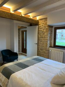 a bedroom with a large bed and a blue chair at OTERO DE CAMPOO in Espinilla