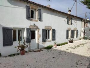 una casa blanca con persianas y plantas negras en La petite Charentaise, en Saint-Christophe