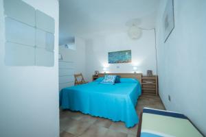 Un dormitorio con una cama azul y una silla. en Le Sunrise - Appartamenti a 350 mt dal mare e con giardino privato, en Cala Liberotto