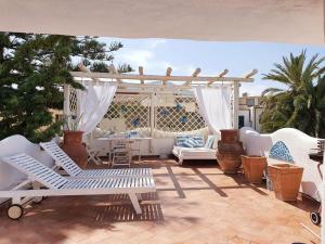 a patio with white chairs and a pergola at Le Andira - Monolocali finemente arredati a pochi passi dal centro storico di Orosei in Orosei