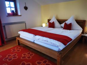 a bedroom with a large bed with red and white pillows at Ferienwohnung Alpenlodge in Rieden am Forggensee