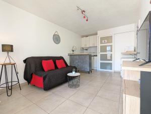 uma sala de estar com um sofá preto e uma cozinha em Appartement rénové avec parking privatif ,à 2min de la plage em Cap d'Agde