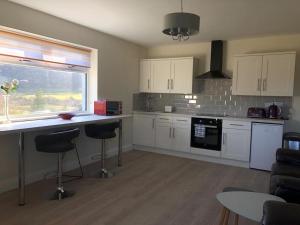 a kitchen with white cabinets and a counter with stools at Oak Tree Lodge in Westport