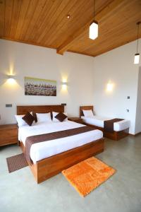 two beds in a bedroom with wooden ceilings at Icy Falls - Ohiya in Ohiya