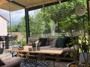 a patio with a couch and a wooden table at Feel@Home De Westhoek in Koekelare