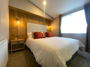 Un dormitorio con una gran cama blanca y una ventana en Daphne's Lodge, en Mawgan Porth
