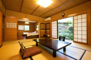a living room with a table and a bedroom at Kurokawa Onsen Oku no Yu in Minamioguni