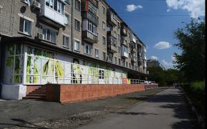 a building with a wall of windows on a street at Квартира-студия в центре с балконом с белым постельным, рядом с Dostyk Mall in Petropavlovsk