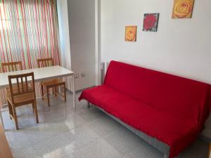 a living room with a red couch and a table at El Medano . Oceanviews, Amazing Sunset in El Médano