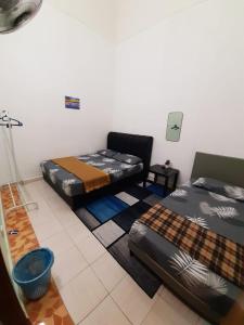 two beds in a room with mats on the floor at AMZ HOMESTAY in Masjid Tanah +2 photos