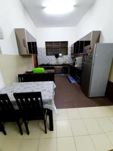 a kitchen with a table and a refrigerator at AMZ HOMESTAY in Masjid Tanah