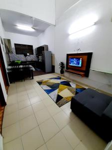 AMZ HOMESTAY في مسجد طنة: غرفة معيشة مع أريكة وتلفزيون بشاشة مسطحة