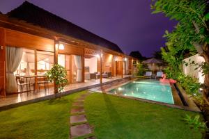 a patio area with a pool and lawn chairs at Canggu Wooden Green Paradise in Canggu
