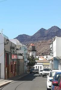 una strada cittadina con torre dell'orologio con una montagna sullo sfondo di Apartamento La Aldea Pueblo Gran Canaria 2B a San Nicolás