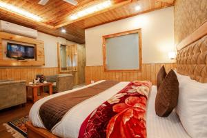 a bedroom with a bed and a television in a room at Hukam's Holiday Home in Kasol