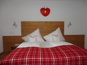 ein Bett mit zwei Kissen und einem roten Herz an der Wand in der Unterkunft Alpenferienwohnung Strickner in Neustift im Stubaital