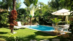 uma piscina num quintal com uma mesa e um guarda-sol em La Tropezina em Búzios