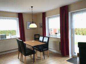 a dining room with a table and chairs and windows at Ferienwohnungen Koch EG adult only in Wangerland