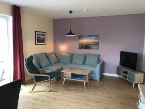 a living room with a blue couch and a tv at Ferienwohnungen Koch EG adult only in Wangerland