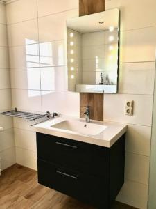 a bathroom with a sink and a mirror at Ferienwohnungen Koch EG adult only in Wangerland