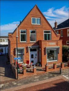 una casa de ladrillo con una mesa y sillas delante de ella en Weltevreden, en Noordwijk