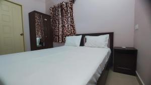 een slaapkamer met een groot wit bed en een spiegel bij Sumithra Apartment in Pondicherry