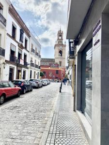 une rue pavée avec une tour de l'horloge et un bâtiment dans l'établissement Fantástico Apto. en el centro histórico de Sevilla, à Séville
