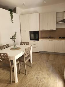 a kitchen with a table and chairs and a kitchen with white cabinets at A-marè - CasaVacanza in Trappeto