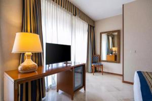 a living room with a television and a desk at Comfort Hotel Fiumicino Airport in Fiumicino