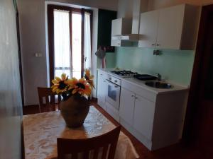 La meriggia ampio appartamento con terrazza esclusiva في أنكونا: مطبخ مع طاولة عليها إناء من الزهور