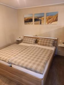 uma cama num quarto com três pinturas na parede em City-Apartment Rietberg em Rietberg