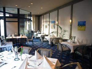 una sala da pranzo con tavoli e sedie bianchi di Hotel Stadt Hamm a Hamm