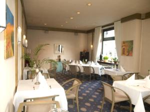 ein Esszimmer mit weißen Tischen und Stühlen in der Unterkunft Hotel Stadt Hamm in Hamm