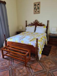 a bedroom with a bed with a wooden frame and a bench at Djarfogo house in S&atilde;o Filipe