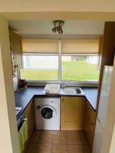 a kitchen with a washing machine and a window at Chalet Escapes in Kidwelly